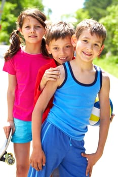 Portrait of three embracing children looking at camera and smiling