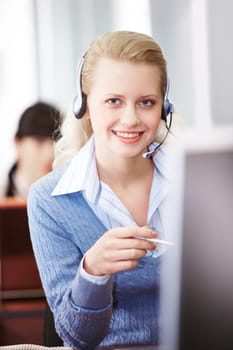 Pretty secretary speaking on headphone in the office