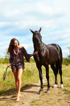 Image of barefoot female walking down path with purebred horse outdoors