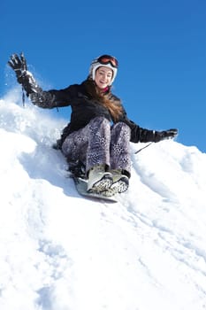 Portrait of happy girl riding on snowboard in winter