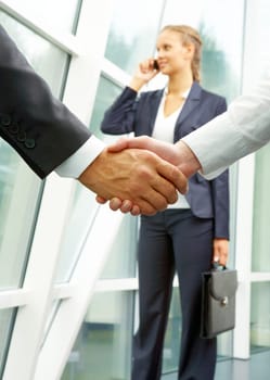 Photo of handshake of business partners after striking deal with calling female on background