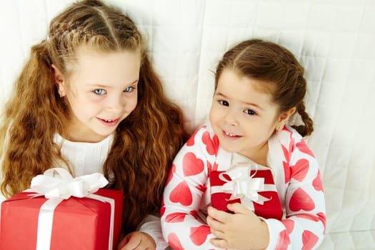 Portrait of happy girls with gifts looking at camera and smiling