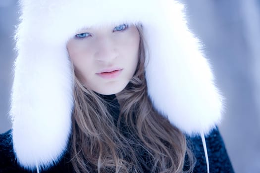 Portrait of attractive young woman wearing white fur cap looking at camera