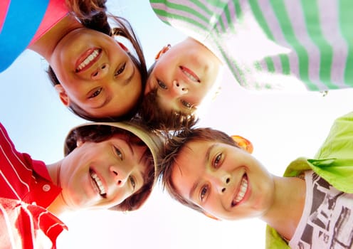 Below view of several happy teens standing head by head to each other
