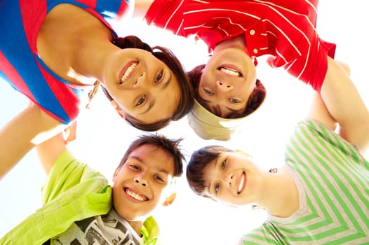 Below view of several happy teens standing head by head to each other