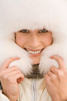 Portrait of beautiful female wearing pure white fur cap and smiling