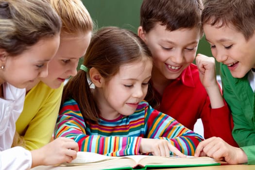 Portrait of friendly group reading book in classroom