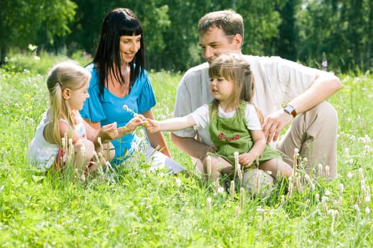 Portrait of happy family sitting on the lawn in the forest