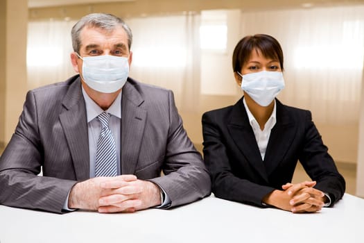 Portrait of two business partners in protective masks looking at camera