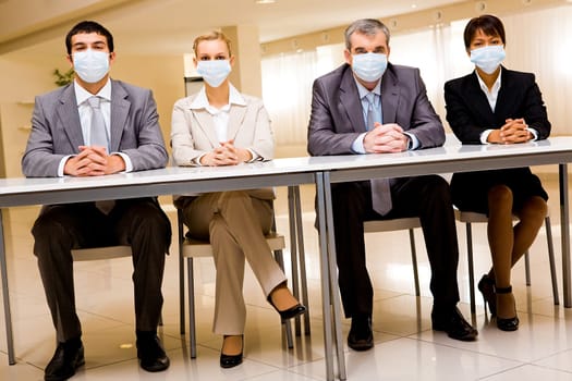 Portrait of group of business partners in protective masks looking at camera