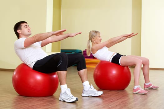 A man and a woman making exercises on balls