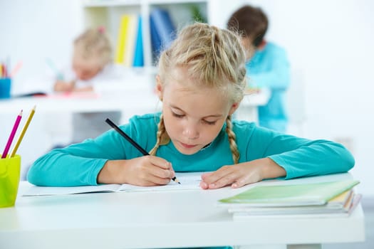 Portrait of lovely girl drawing with classmates on background