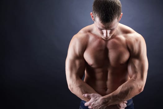 Image of shirtless man looking downwards with his arms crossed by stomach