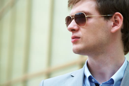Handsome businessman looking through sunglasses outside