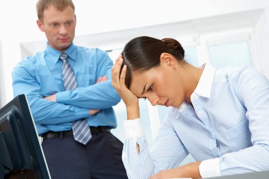 Image of a young upset businesswoman, her chief standing at her distressed