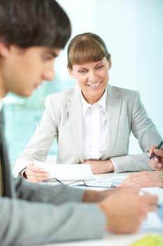 Positive businesswoman sitting at table with her colleagues