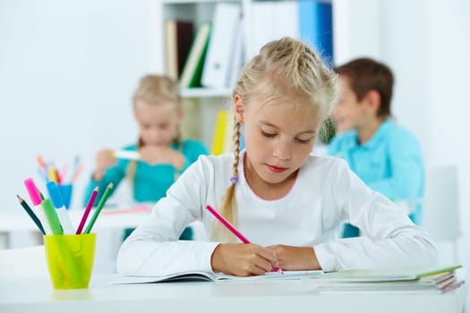 Portrait of lovely girl drawing with classmates on background