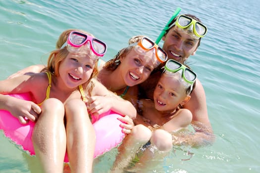 Portrait of cheerful family in aqualungs looking at camera from water