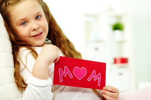 Portrait of happy girl showing envelope with congratulation card and looking at camera