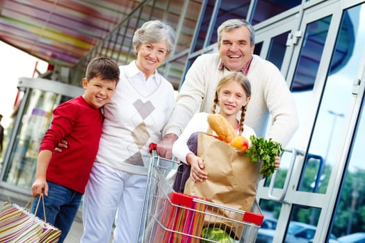 Portrait of happy grandparents and grandchildren near supermarket