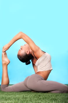Portrait of happy young woman doing stretching exercise on grass