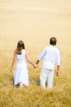 Image of couple holding by hands and walking along the field