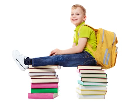 A smiling boy with satchel sitting on two heaps of books