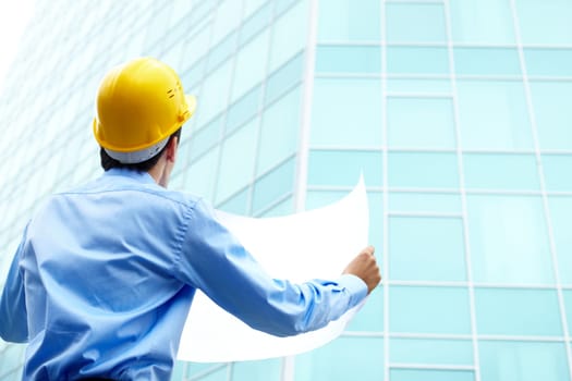 Rear view of architect looking comparing housing project with building