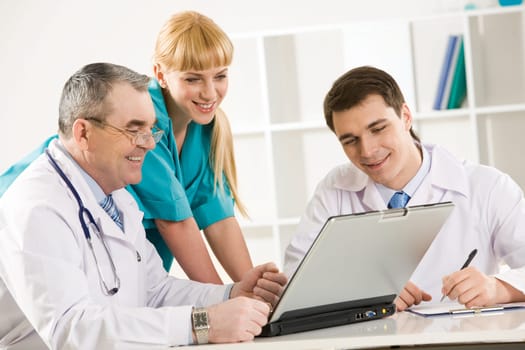 Group of therapists looking at laptop screen and discussing new method of treatment