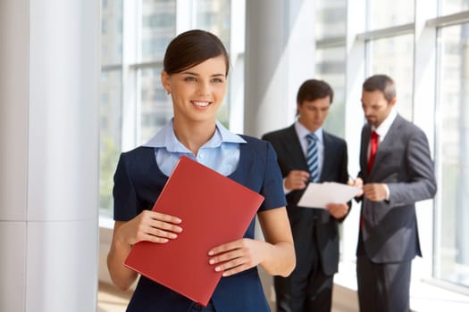 Portrait of confident female looking aside with working colleagues at background