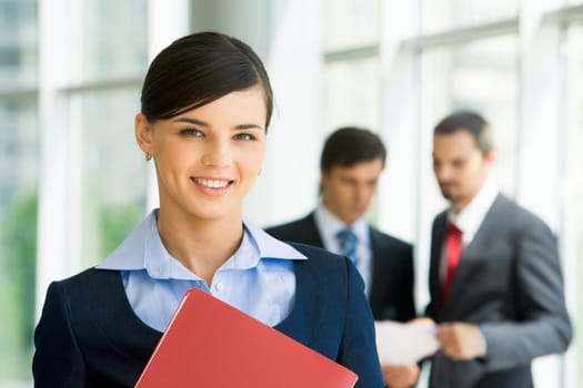 Portrait of confident female looking at camera with her colleagues at background