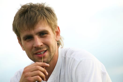 Portrait of handsome man looking at camera on a sky background