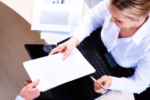 Above view of businesswoman looking at paper during meeting before signing it