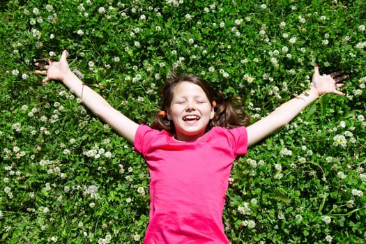 Portrait of a joyful little girl lying on grass