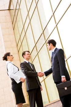 Portrait of two business partners handshaking after making agreement with pretty employee near by
