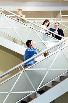 Photo of busy partners communicating while going upstairs in office building