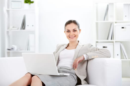 Portrait of smiling businesswoman with laptop looking at camera in office