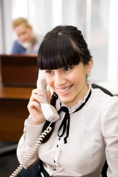Pretty secretary speaking on the phone in the office