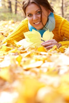 Image of resting young woman lying on foliage in autumn