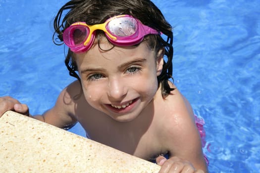 beautiful little girl smiling in  blue water with pink goggles