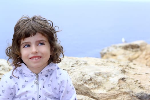 brunette little girl funny gesture portrait near sea blue eyes