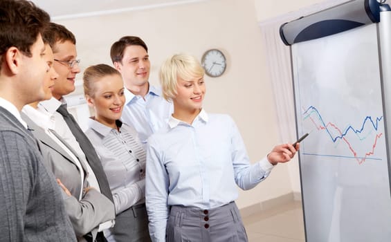 Image of business partners looking at whiteboard and listening to smart employee in office
