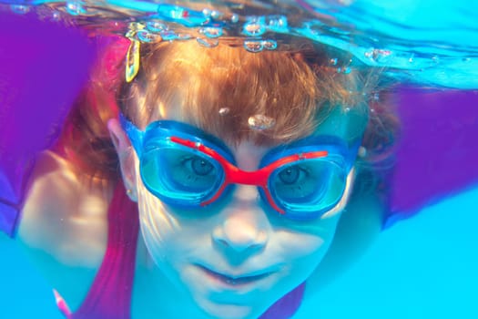 Underwater swimming girl goggles blue water portrait