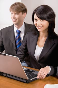 Responsible woman is smiling and sitting at the table with business man near by