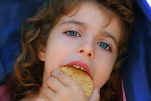 Little girl eating biscuit closeup face portrait