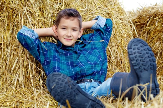 Happy lad lying on hay in countryside