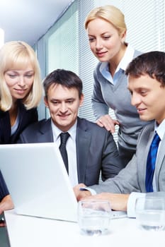 Four business people working with laptop in office