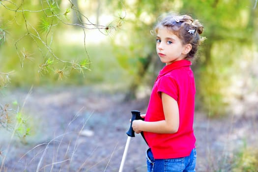 Beautiful kid girl in park forest with trekking pole