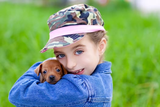little girl with pet puppy mascot mini pinscher in outdoor green grass