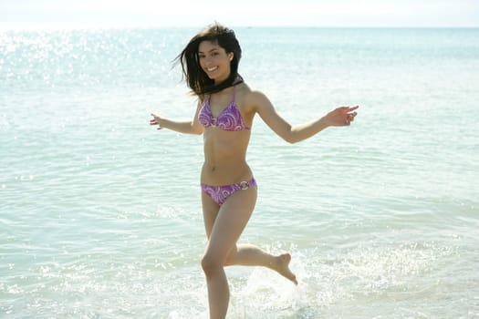 beautiful woman running on the beach, purple bikini